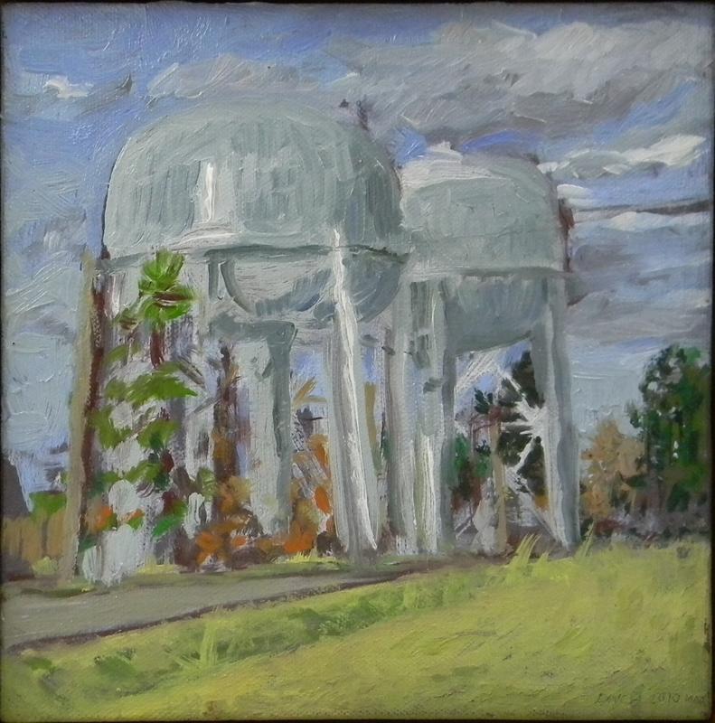 Two Water Towers whose flattend, spherical bladders are raise approximately 100 feet off the ground, supported by four large, tubular legs and wire rigging.  The blue grey paint reflects the sunset